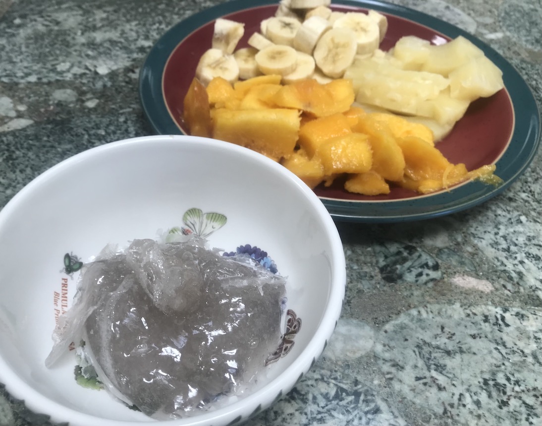 Bowl of grey gel, with fruit behind