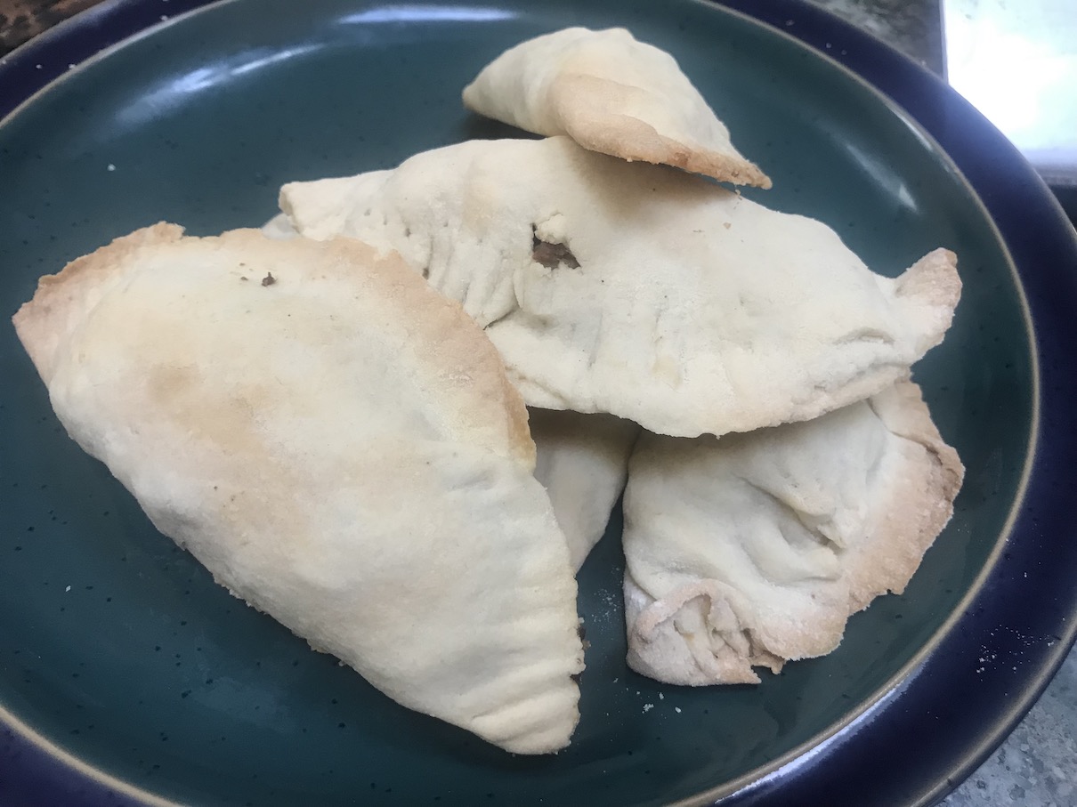 Six empanadas stacked on a plate